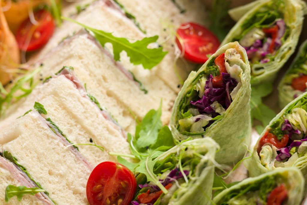 Fresh sandwiches and wraps with greens and cherry tomatoes, perfect for a quick lunch.