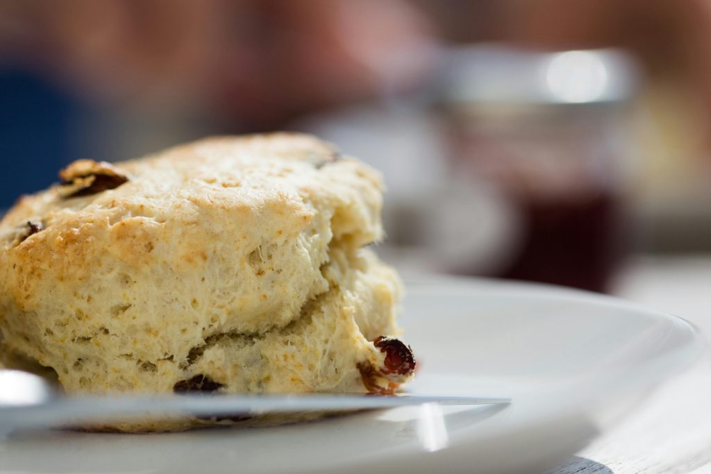 Delicious close-up of a freshly baked scone with raisins on a white plate.